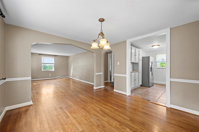 345 Franklin Dr, Peters Twp, PA 15241 - empty room featuring arched walkways, light wood-type flooring, and a chandelier