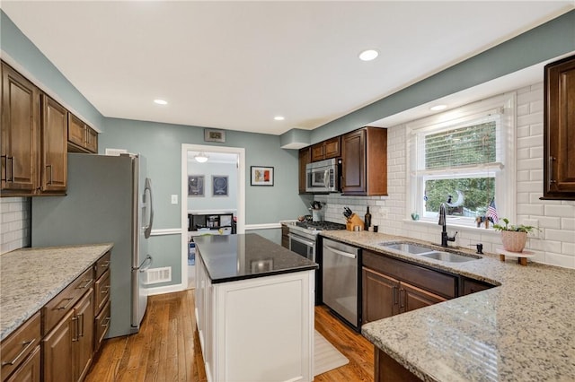 130 Kent Dr, Upper St Clair, PA 15241 - kitchen featuring stainless steel appliances, light wood-style flooring, backsplash, a kitchen island, and light stone countertops
