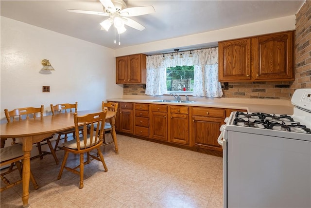 2509 Spring St, Arlington, PA 15210 - kitchen with white gas range, brown cabinetry, light countertops, ceiling fan, and light floors