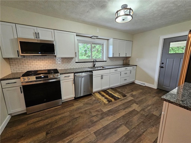 946 Herman Rd, Summit Twp But, PA 16002 - kitchen featuring stainless steel appliances, dark wood finished floors, tasteful backsplash, white cabinets, and dark stone countertops