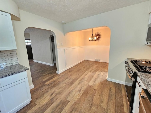 946 Herman Rd, Summit Twp But, PA 16002 - kitchen featuring stainless steel appliances, arched walkways, light wood-style flooring, dark stone counters, and a chandelier