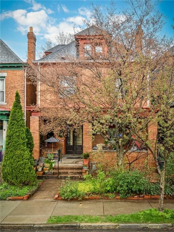 609 N Beatty, East Liberty, PA 15206 - view of front of property featuring brick siding, a shingled roof, and a chimney