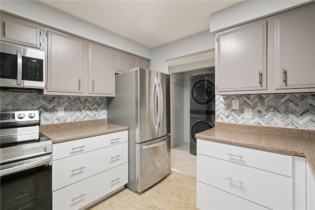 307 S Dithridge St Unit 207, Oakland, PA 15213 - kitchen with appliances with stainless steel finishes, stacked washing machine and dryer, tasteful backsplash, gray cabinets, and light tile patterned floors