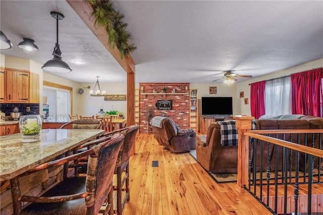 4627 Water Level Rd, Milford Twp, PA 15557 - dining room featuring light wood-type flooring, ceiling fan, a chandelier, and a brick fireplace