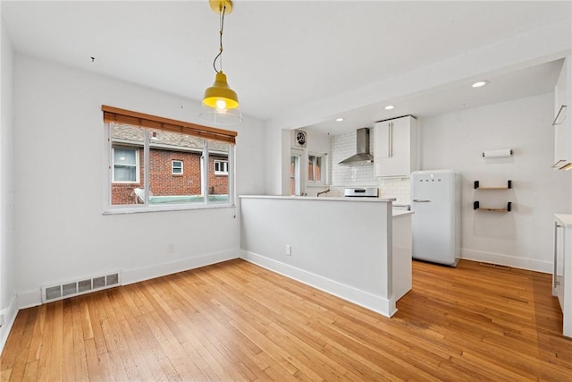 4207 Post St, Lawrenceville, PA 15201 - kitchen with wall chimney exhaust hood, freestanding refrigerator, white cabinetry, light wood-style floors, and recessed lighting