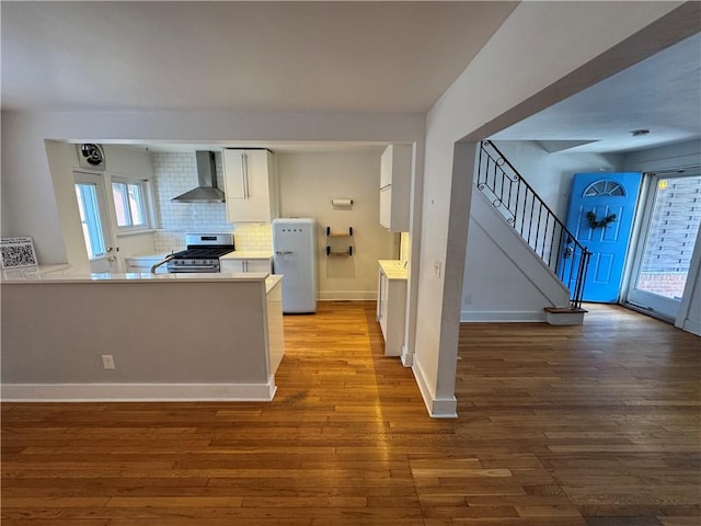 4207 Post St, Lawrenceville, PA 15201 - kitchen with wall chimney range hood, stainless steel range with gas cooktop, white cabinetry, decorative backsplash, and light countertops