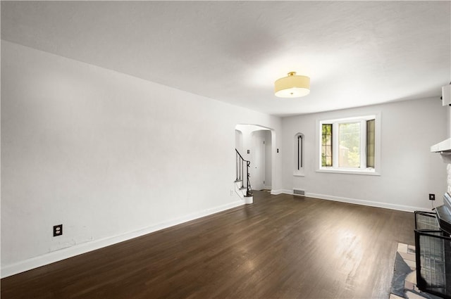 2401 Valera Ave, Carrick, PA 15210 - unfurnished living room featuring arched walkways, dark wood-style flooring, and stairs