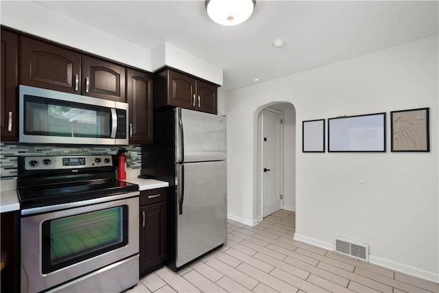 2401 Valera Ave, Carrick, PA 15210 - kitchen featuring stainless steel appliances, arched walkways, light countertops, and dark brown cabinetry