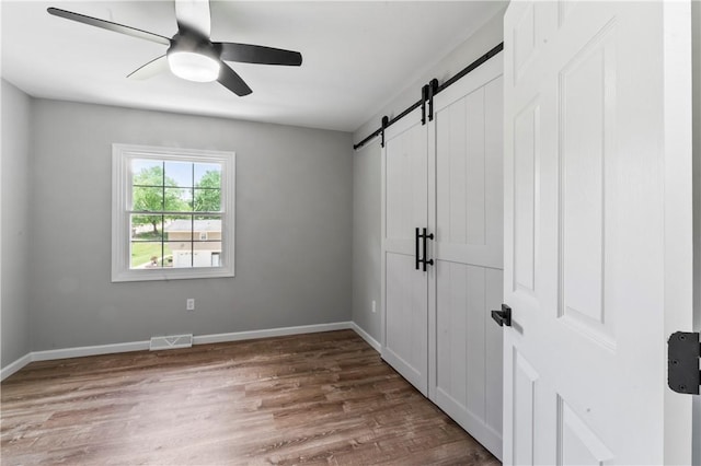 117 Heather Dr, Center Twp Bea, PA 15061 - unfurnished bedroom featuring a barn door, wood finished floors, and ceiling fan