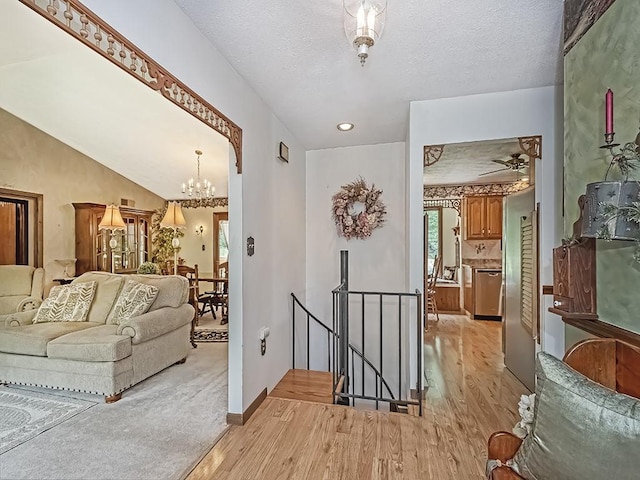 4779 State Route 819, Bell Twp, PA 15613 - hallway with an upstairs landing, light wood-type flooring, a chandelier, and a textured ceiling