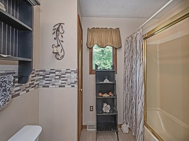 4779 State Route 819, Bell Twp, PA 15613 - bathroom with tasteful backsplash, shower / bath combination with curtain, a textured ceiling, and wood finished floors