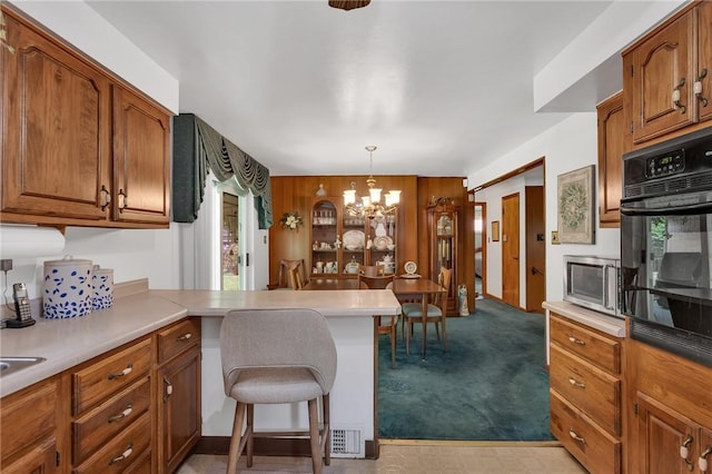 4636 Bowes Ave, West Mifflin, PA 15122 - kitchen featuring black oven, stainless steel microwave, brown cabinetry, and a chandelier