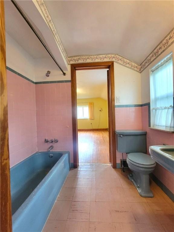 1176 Colgate Dr, Monroeville, PA 15146 - bathroom with tile walls, vaulted ceiling, washtub / shower combination, and wainscoting