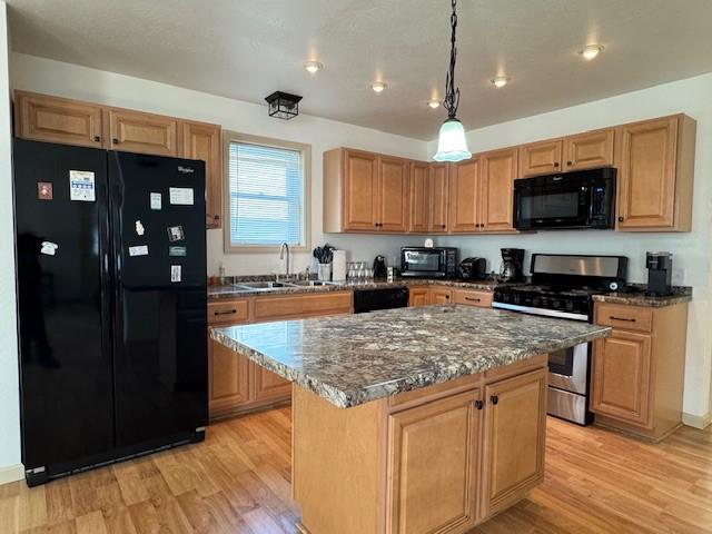 436 Lloyd Ave, Latrobe, PA 15650 - kitchen with black appliances, light wood-style floors, a center island, decorative light fixtures, and dark stone counters