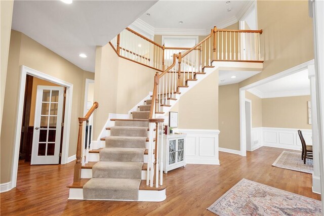 8010 Sherwood Dr, Collier Twp, PA 15142 - staircase featuring wood finished floors, crown molding, a towering ceiling, and wainscoting