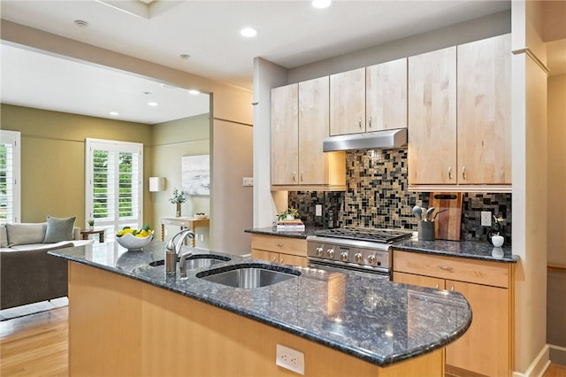 140 N Woodland Rd, Shadyside, PA 15232 - kitchen with stainless steel range, under cabinet range hood, backsplash, a center island with sink, and dark stone counters