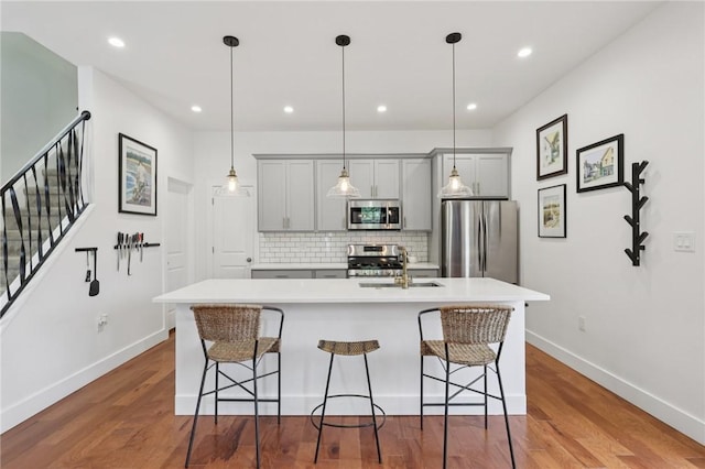 3130 Dobson St, Polish Hill, PA 15219 - kitchen featuring appliances with stainless steel finishes, gray cabinets, decorative backsplash, light countertops, and a center island with sink