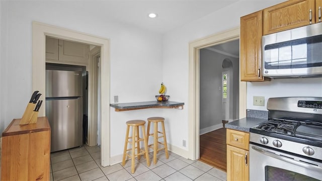 148 Stanton Ct E, Stanton Heights, PA 15201 - kitchen featuring stainless steel appliances, arched walkways, light tile patterned flooring, dark countertops, and a kitchen breakfast bar