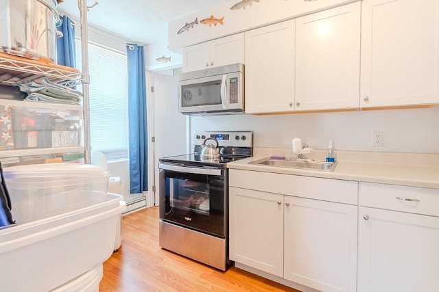 5801 Lincoln Ave, Export, PA 15632 - kitchen with stainless steel appliances, a baseboard radiator, white cabinetry, light countertops, and light wood-style floors