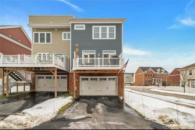 323 Osona Ln, Marshall, PA 16046 - snow covered back of property with asphalt driveway, an attached garage, brick siding, and a deck