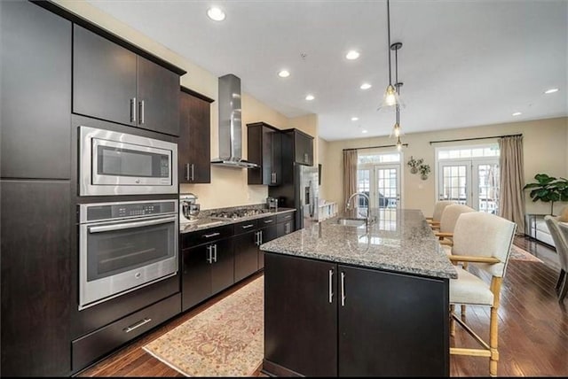 323 Osona Ln, Marshall, PA 16046 - kitchen with stainless steel appliances, wall chimney range hood, a center island with sink, open floor plan, and wood finished floors