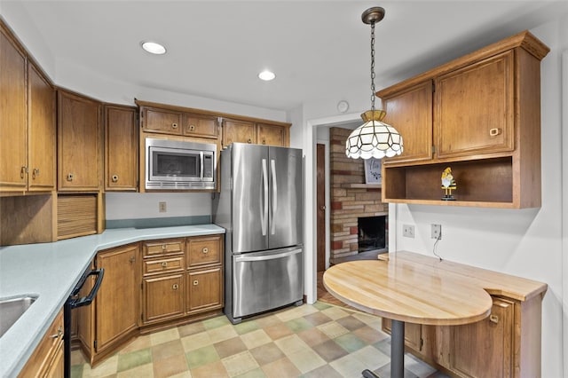 103 Drood Ln, Ross Twp, PA 15237 - kitchen featuring stainless steel appliances, brown cabinetry, light countertops, pendant lighting, and a fireplace
