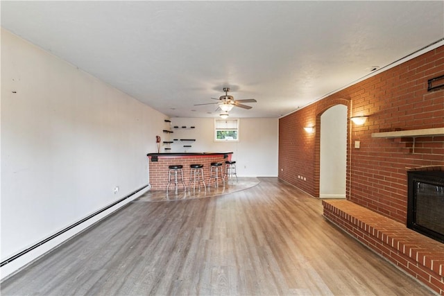 130 Clare Dr, South Strabane, PA 15301 - unfurnished living room with a baseboard radiator, wood finished floors, a dry bar, brick wall, and a ceiling fan