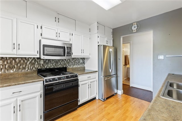 130 Clare Dr, South Strabane, PA 15301 - kitchen with stainless steel appliances, tasteful backsplash, light wood-type flooring, and white cabinetry