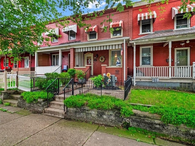 townhome / multi-family property with covered porch and brick siding
