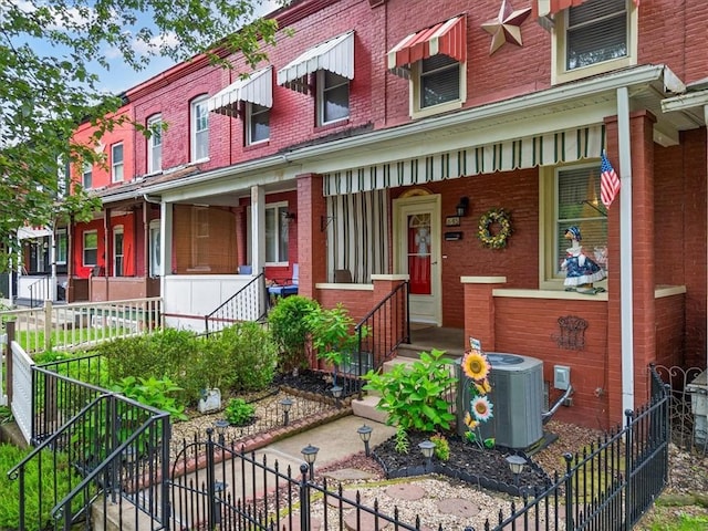 townhome / multi-family property featuring a porch, brick siding, and stairs