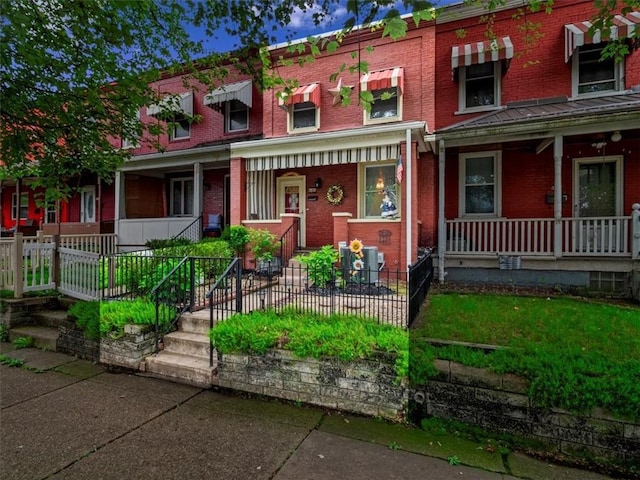 townhome / multi-family property featuring a porch and brick siding
