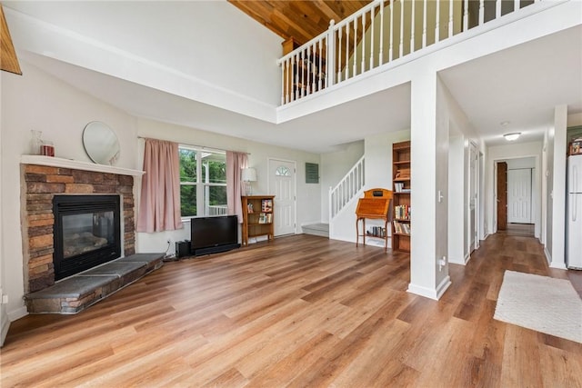 135 Preacher Rd, East Huntingdon, PA 15639 - unfurnished living room featuring stairway, a high ceiling, wood finished floors, and a stone fireplace