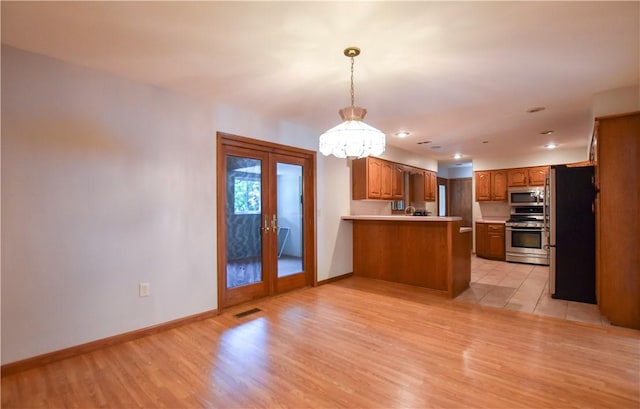 150 Morgan Rd, Penn Twp But, PA 16002 - kitchen with stainless steel appliances, a peninsula, a chandelier, french doors, and brown cabinets
