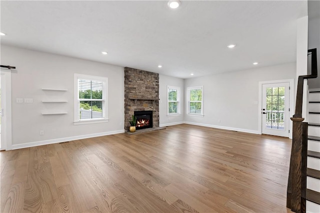 107 Abigail Dr, Adams Twp, PA 16046 - unfurnished living room with wood finished floors, stairs, a stone fireplace, recessed lighting, and a barn door