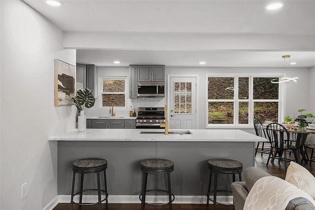 1171 Arrowood Dr, Mt Lebanon, PA 15243 - kitchen with gray cabinetry, stainless steel appliances, a breakfast bar area, light countertops, and decorative backsplash