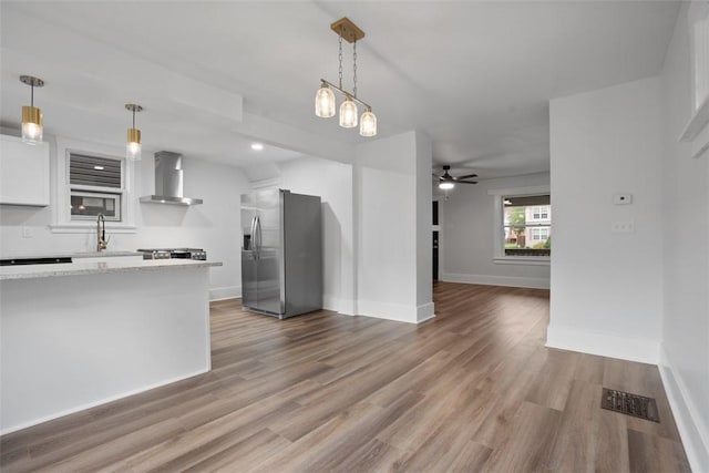 1341 4th Ave, Coraopolis, PA 15108 - kitchen featuring stainless steel fridge with ice dispenser, wall chimney range hood, a ceiling fan, white cabinets, and wood finished floors