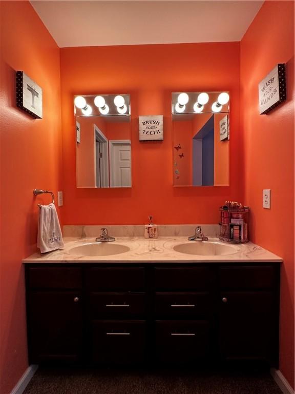 bathroom with double vanity and baseboards