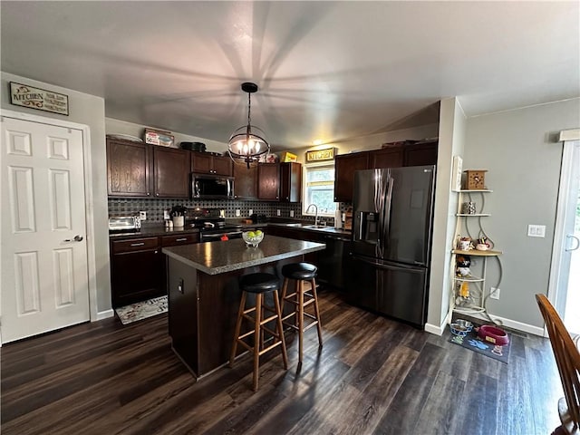 kitchen featuring fridge with ice dispenser, stainless steel microwave, range with electric stovetop, dark countertops, and dark wood-style flooring