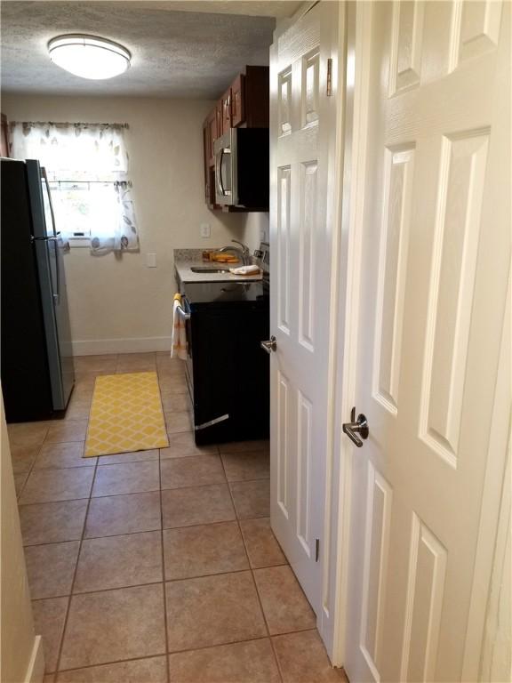 2807 Middle Rd, Hampton, PA 15116 - kitchen featuring stainless steel microwave, freestanding refrigerator, range with electric cooktop, light tile patterned floors, and light countertops