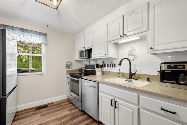3118 Ridge Rd, South Park, PA 15129 - kitchen featuring appliances with stainless steel finishes, white cabinetry, backsplash, a textured ceiling, and light wood-style floors