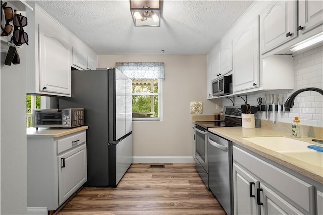 3118 Ridge Rd, South Park, PA 15129 - kitchen featuring stainless steel appliances, backsplash, white cabinets, a textured ceiling, and wood finished floors
