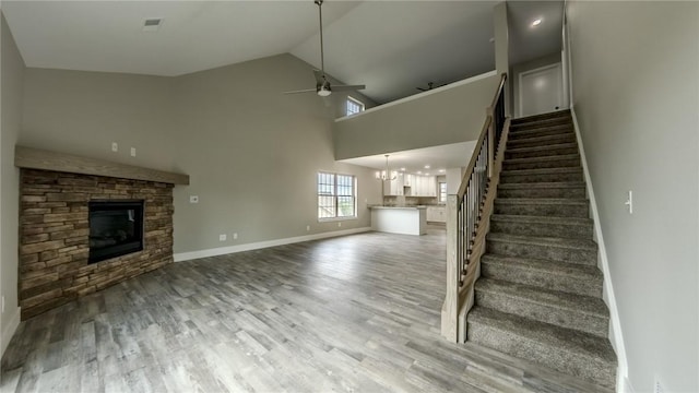 740 Sandstone Way, Rostraver, PA 15012 - unfurnished living room featuring a stone fireplace, stairs, ceiling fan, wood finished floors, and a chandelier