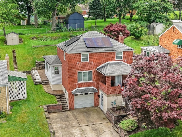 4457 Woodhill Dr, Munhall, PA 15120 - view of front facade featuring a shed, driveway, an attached garage, roof mounted solar panels, and brick siding