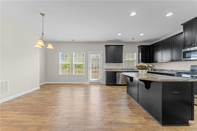 2804 Pointe View Dr, Adams Twp, PA 16046 - kitchen featuring appliances with stainless steel finishes, dark cabinets, light wood finished floors, a center island, and a breakfast bar area