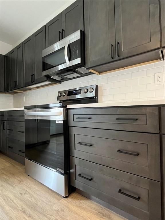 843 Ledlie St, Hill District, PA 15219 - kitchen featuring appliances with stainless steel finishes, light wood-style flooring, decorative backsplash, and light countertops