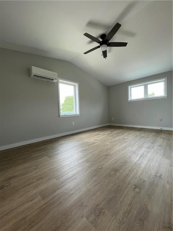 843 Ledlie St, Hill District, PA 15219 - spare room featuring a wall mounted AC, vaulted ceiling, plenty of natural light, ceiling fan, and wood finished floors