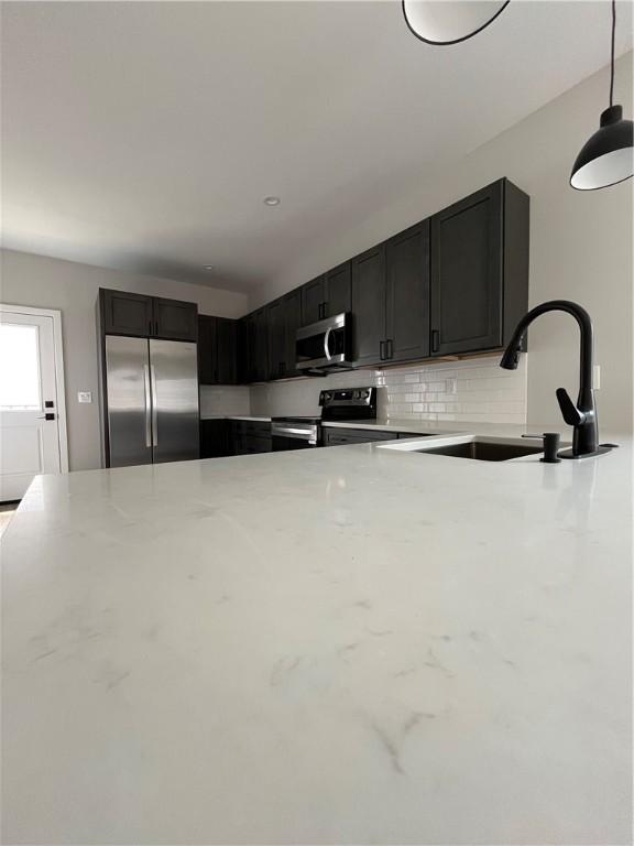 843 Ledlie St, Hill District, PA 15219 - kitchen with appliances with stainless steel finishes, light stone countertops, backsplash, and decorative light fixtures