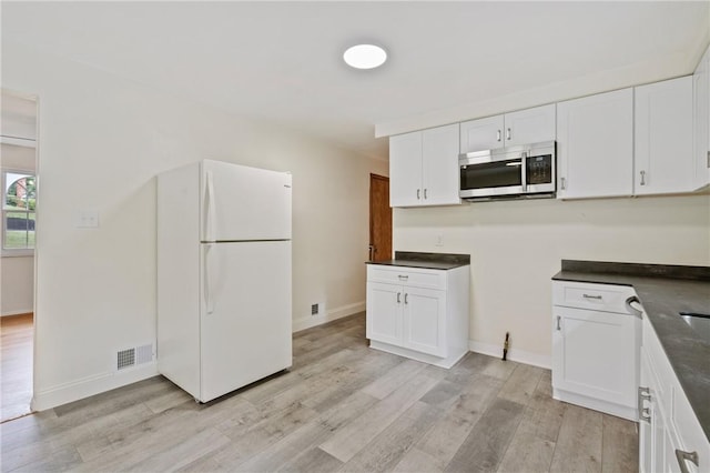 4421 Logan Ferry Rd, Murrysville, PA 15668 - kitchen featuring stainless steel microwave, freestanding refrigerator, light wood-style flooring, white cabinetry, and dark countertops