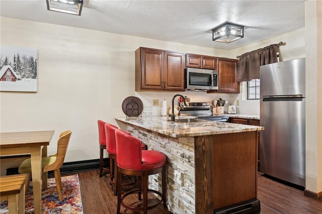 1147 Tanyard Ln, Hidden Valley, PA 15502 - kitchen with stainless steel appliances, dark wood-type flooring, a peninsula, a breakfast bar area, and light stone counters