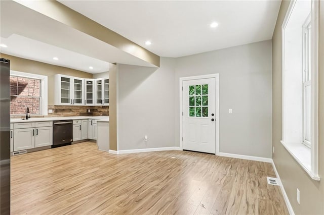 515 Peebles St, Wilkinsburg, PA 15221 - kitchen with dishwasher, light countertops, light wood finished floors, glass insert cabinets, and backsplash